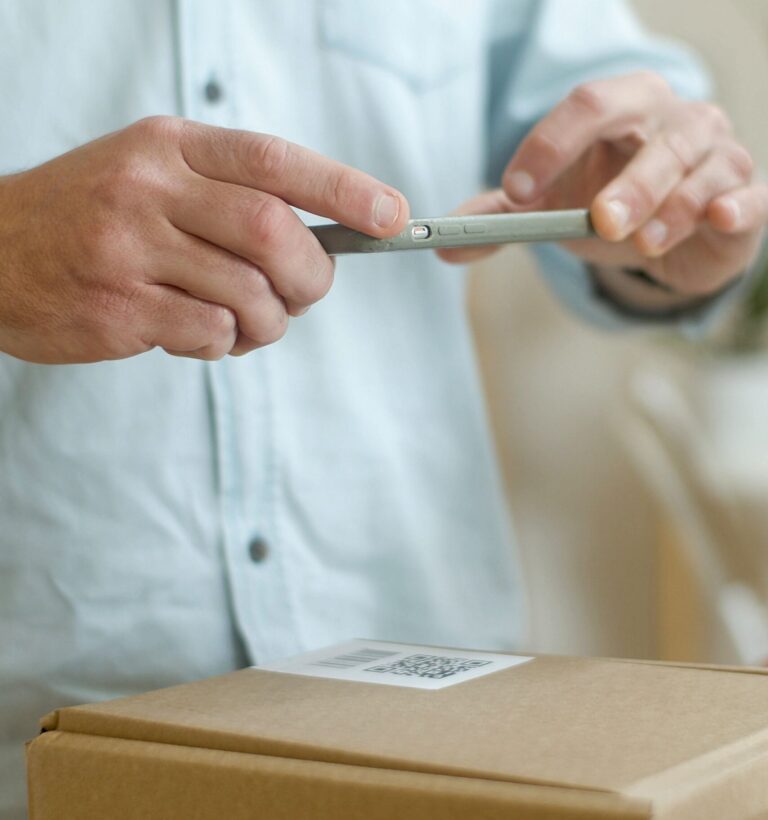 Eine Person scannt den QR-Code auf einem Paket.